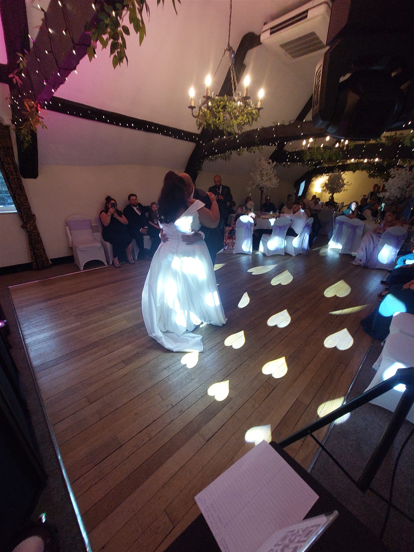 Couple enjoy their first dance with heart-shaped lights on the floor