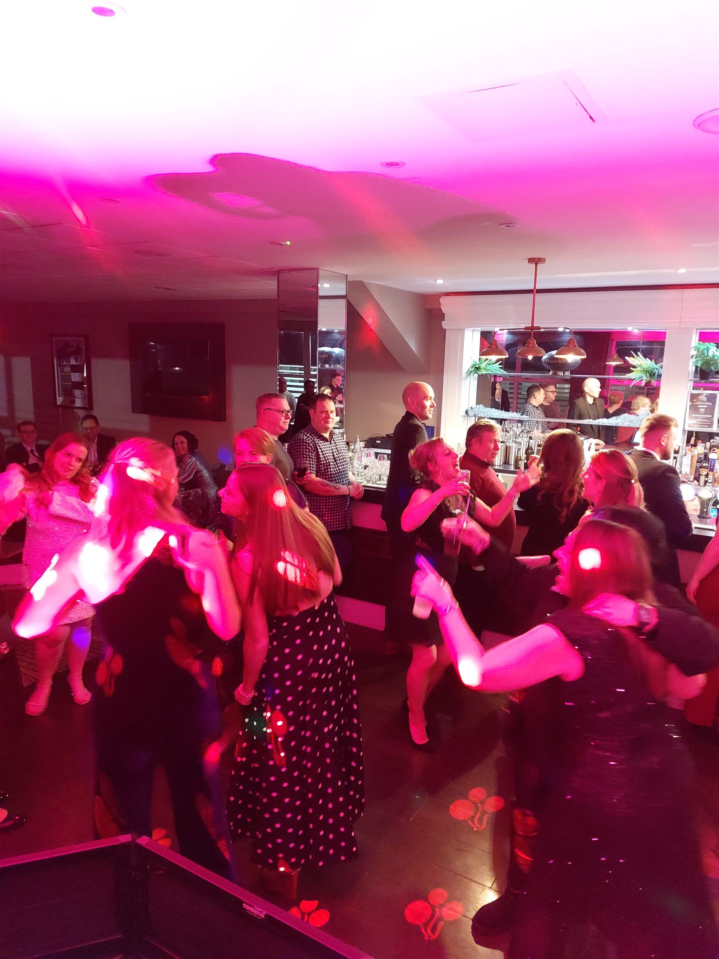 Guests dance at a lively party under pink disco lights