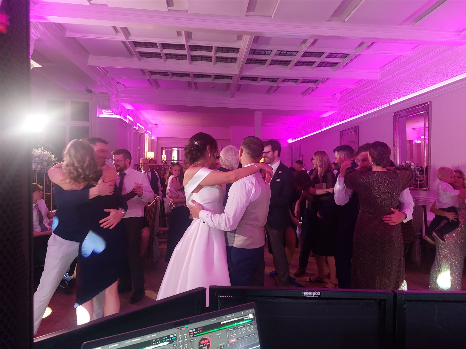 Wedding guests enjoying the dance floor under pink party lights