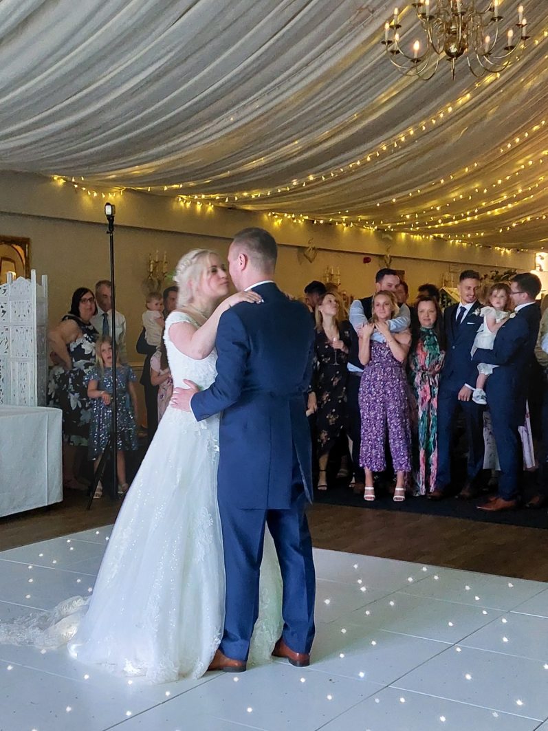 Event Special Bride and groom share a kiss during their first dance, surrounded by guests in celebration.